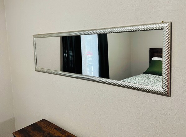 Espejo rectangular con un marco texturizado fijado a la pared.