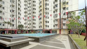 A multi-story residential building with a swimming pool and a small garden area. - Apartemen Cibubur Village KaisarProperty (Kota Depok)