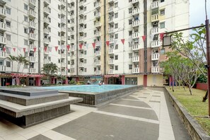 A multi-story residential building with a swimming pool and a small garden area. - Apartemen Cibubur Village KaisarProperty (Kota Depok)