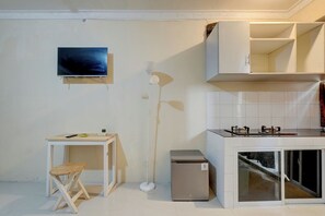 Cozinha compacta com fogão, uma geladeira pequena e um espaço de refeições com mesa e cadeira.