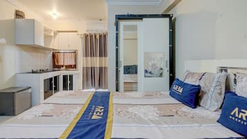 Habitación de hotel con cama, escritorio y kitchenette.