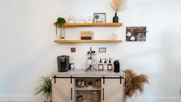 A coffee station with a coffee machine, sugar, tea, and a welcome sign.