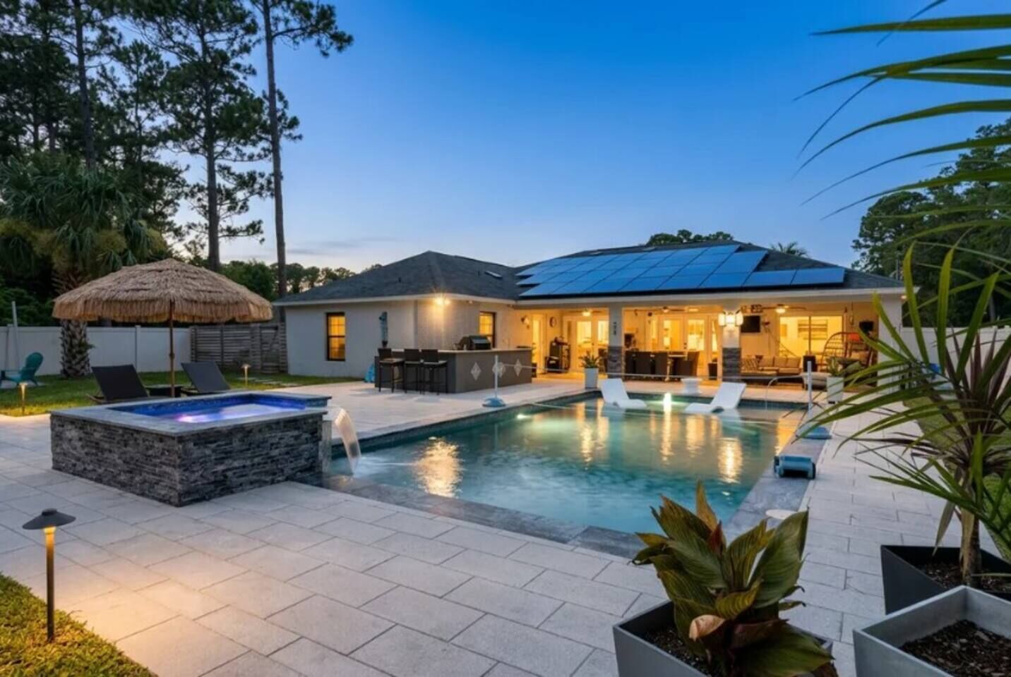 Ein Garten mit Schwimmbad, Whirlpool und überdachter Terrasse.