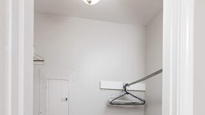 Corredor com porta branca, porta-roupas, interruptor de luz e espelho.