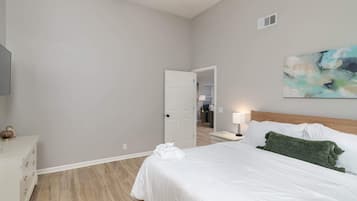 Een hotelkamer met een bed, nachtkastje, lamp en een schilderij aan de muur.