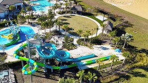 Vue aérienne d’un complexe hôtelier doté d’une grande piscine, de toboggans aquatiques et d’une plage de sable.