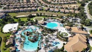 Luchtbeeld van een resort met meerdere zwembaden, een golfbaan en een woongebied met huizen.