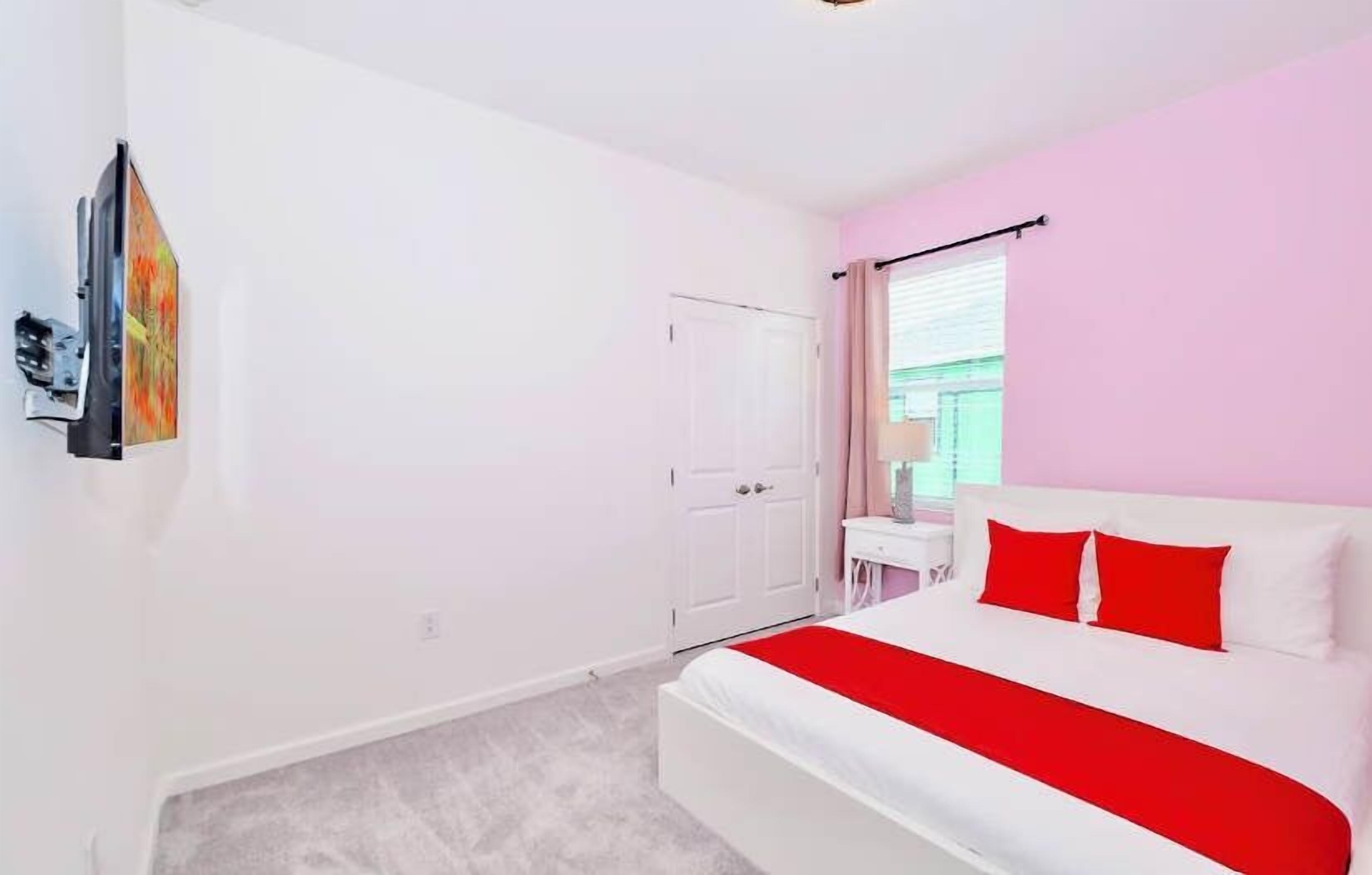 Un dormitorio con cama, armario blanco, ventana con cortinas y una obra de arte colgada en la pared.