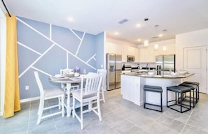 Una cocina moderna con una isla central, muebles blancos y electrodomésticos de acero inoxidable.