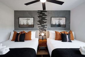 A double room with two beds, a ceiling fan, a nightstand, and artwork on the walls. - Cactus Palms -Pool-Pickleball-Sports Court-Games (Scottsdale)