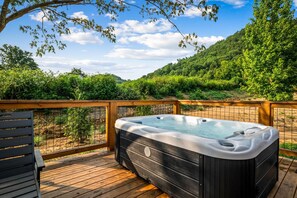 A hot tub on a wooden deck with a view of a forested hillside. - Hodo Springs — Birch | A-Frame | Private Sauna, Hot Tub | River Access | Smokies (Sevierville)