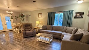 Ein Wohnzimmer mit Sofa, Sessel, Couchtisch, Esstisch, Stühlen und einer Chandelier.