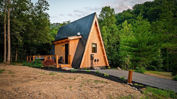 A small wooden cabin with a sloped roof, surrounded by a forested area. - Hodo Springs — Maple | Luxury A-Frame | Private Sauna, Hot Tub | River | Smokies (Sevierville)