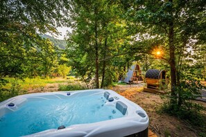 A hot tub surrounded by trees with a wooden structure in the background. - Hodo Springs — Pine | A-Frame | Forest Sauna Path + Hot Tub | Smokies (Sevierville)