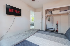 Une chambre à coucher avec un lit, un téléviseur fixé au mur et une armoire contenant divers objets.