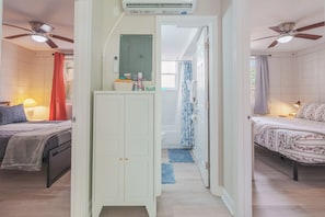 Quarto com cama, guarda-roupa, ventoinha no teto e ar condicionado.