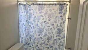 Ein Badezimmer mit Toilette, Waschbecken und Duschvorhang mit Meeresmotiven.