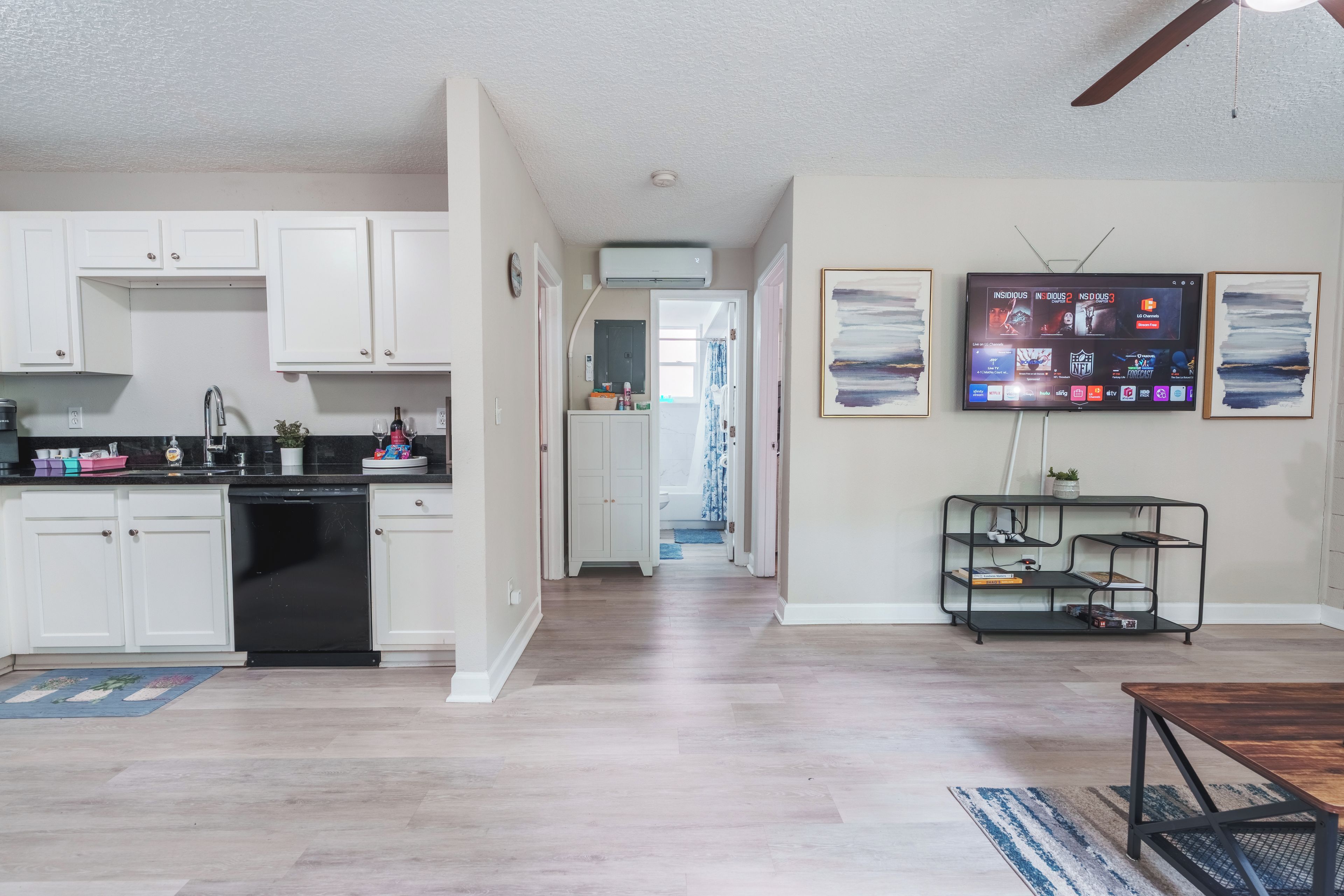 A modern kitchen with white cabinets, a dishwasher, and a dining area with a wooden table and chairs.