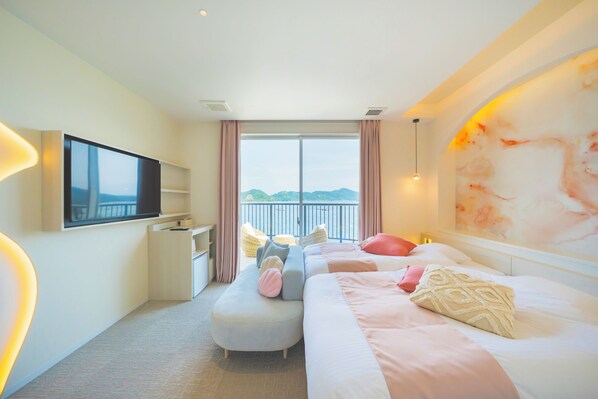 Habitación de hotel con cama, televisión, escritorio, silla y vista al mar.