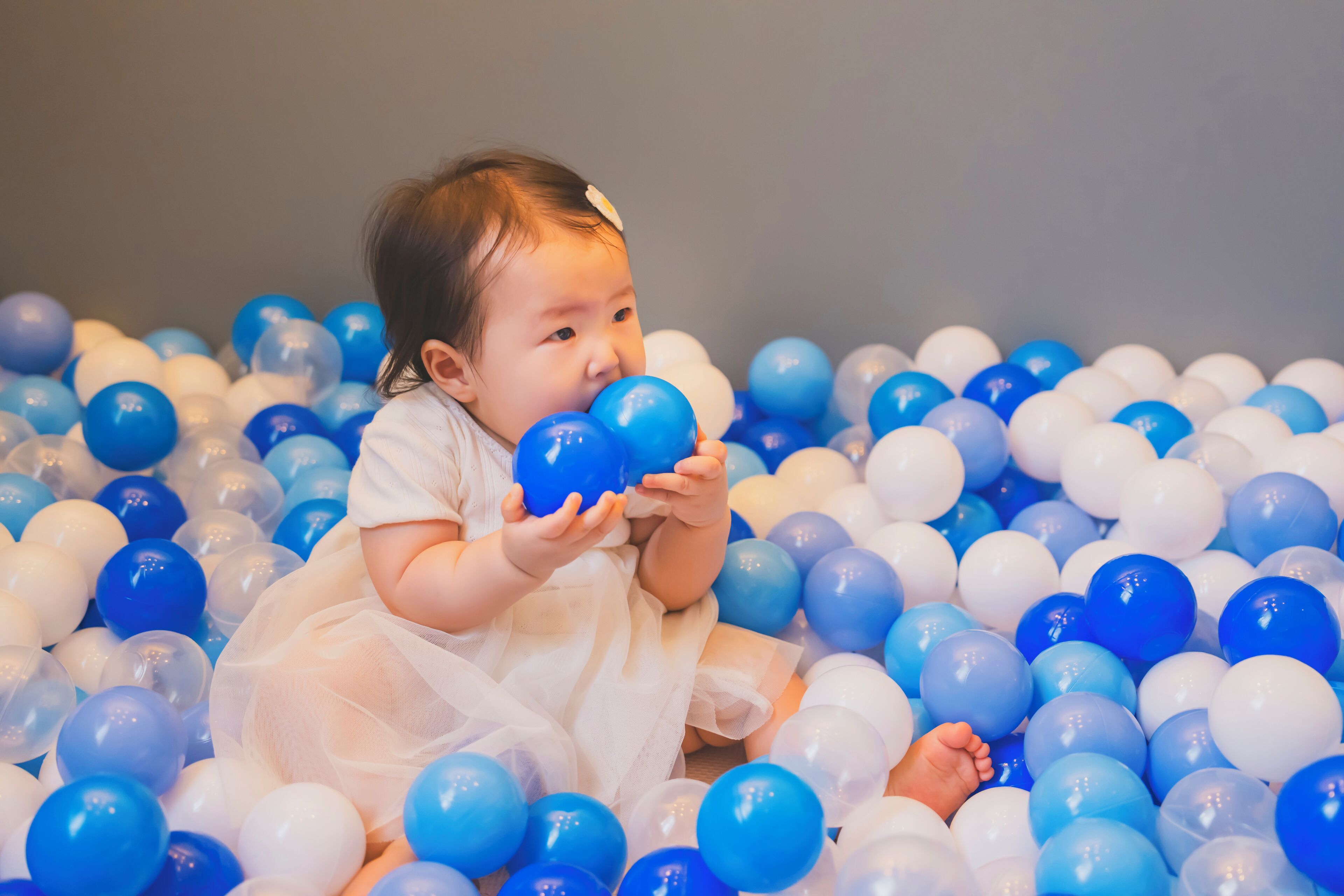 A child surrounded by a large number of blue and white balloons.