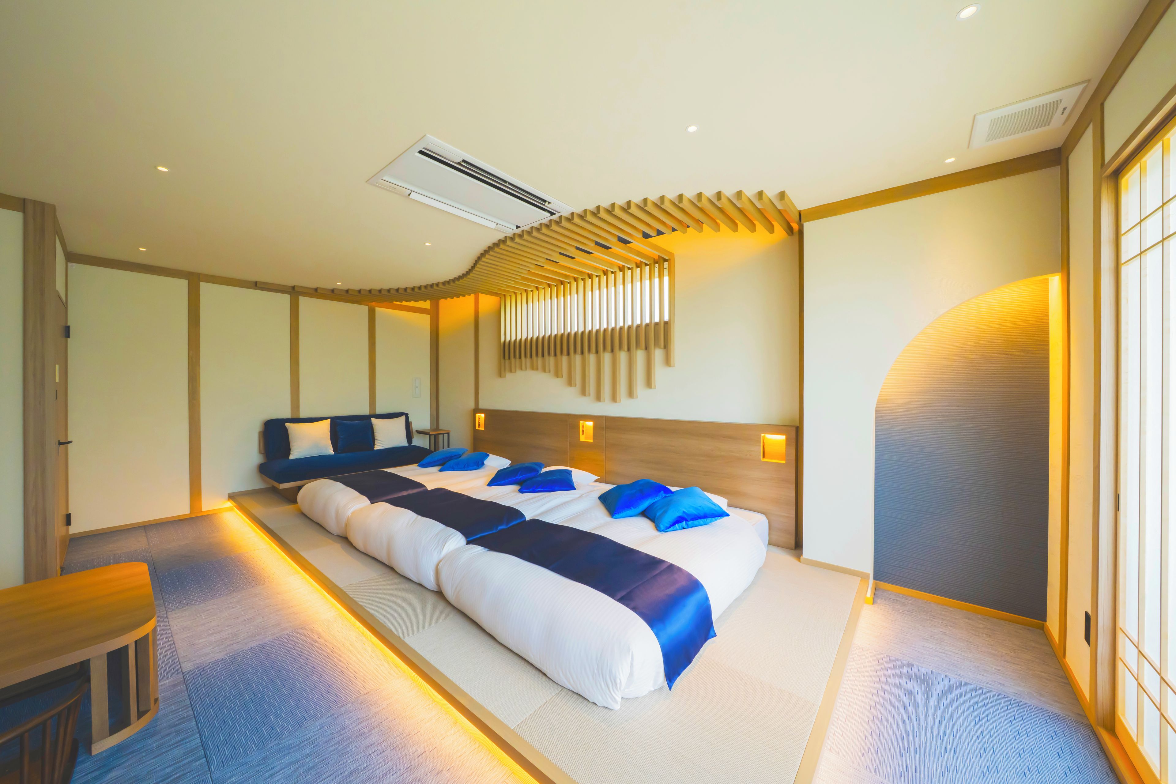 A hotel room with a large bed, a desk, and a wall-mounted air conditioning unit.