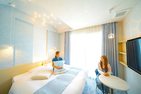 Una habitación de hotel con cama, mesita de noche, televisor y ventana con cortinas.