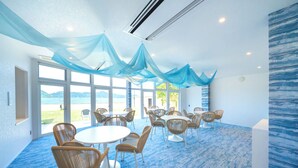 A room with a round table and chairs, large windows, and a view of the outdoors. - Hotel O. Naruto (Naruto)