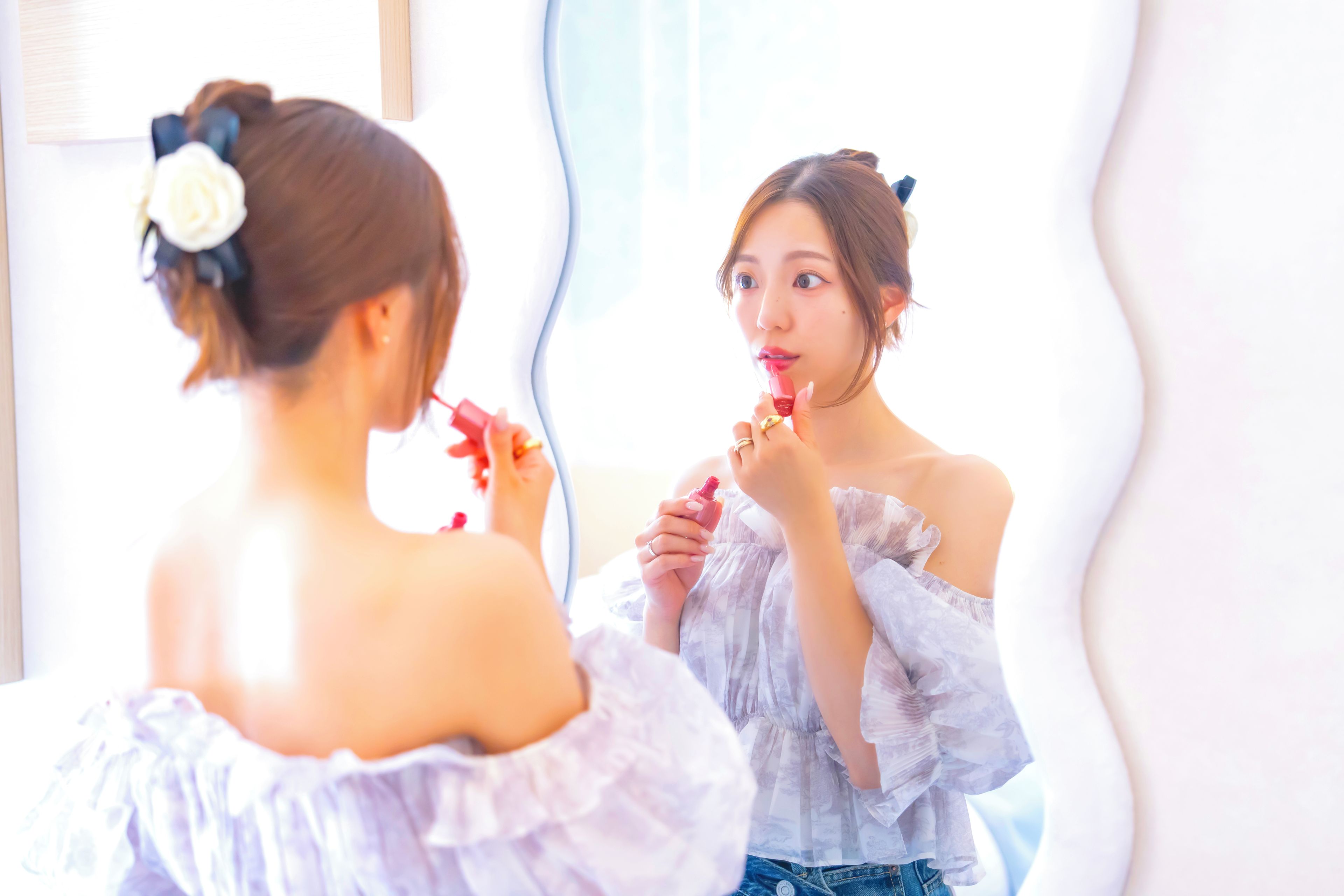 A person applying lipstick in front of a mirror.