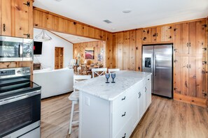 Une cuisine moderne avec un lambris en bois, des appareils électroménagers en acier inoxydable et un plan de travail en marbre.