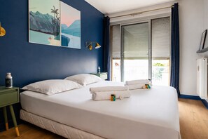 Ein Hotelzimmer mit Bett, Nachttisch, Fenster mit Vorhängen und einem Bild an der Wand.