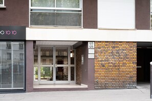A building entrance with a glass door, a visible number '123' on the wall, and a '10 10' sign above the door. - Appartement Sérénité Charonne - Welkeys (Paris)