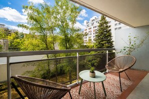 A balcony with wicker chairs, a small table, and a potted plant. - Appartement Sérénité Charonne - Welkeys (Paris)