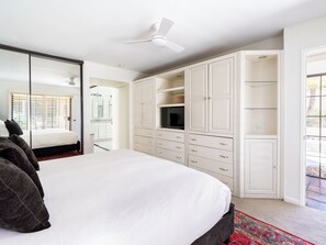Ein Schlafzimmer mit Bett, Kleiderschrank, Fernseher und Deckenventilator.