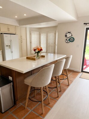 Een moderne keuken met een centraal eiland, witte kastjes en een Snoopy wanddecoratie.