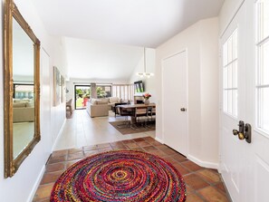 A spacious hallway with a dining area, a sofa, and a TV. - Charming Palm Desert Hideaway in Silver Sands club - Pool, Tennis & Sunshine! (Palm Desert)