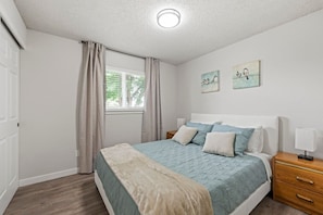 Un dormitorio con cama, mesitas de noche, una ventana con cortinas y decoración en la pared.