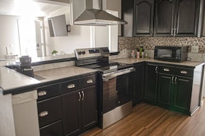 Une cuisine moderne avec des meubles de couleur sombre, des appareils en acier inoxydable et un pare-feu décoratif.