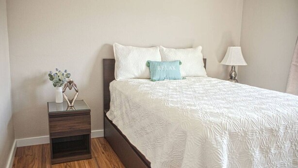 Un dormitorio con una cama, una mesita de noche, una lámpara y un adorno.