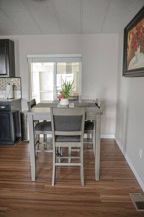 A dining area with a table and chairs, a window, and a kitchen area with cabinets.