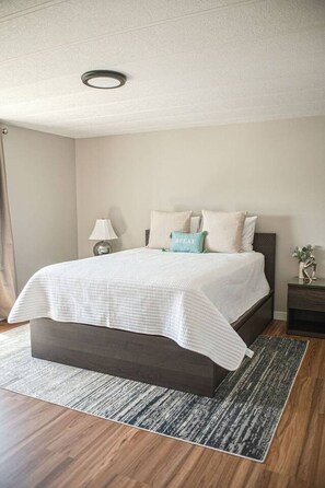 A bedroom with a bed, bedside tables, a lamp, and a nightstand.