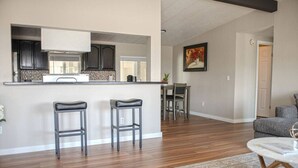 Una cocina moderna con armarios oscuros, una encimera blanca y un comedor con mesa y sillas.