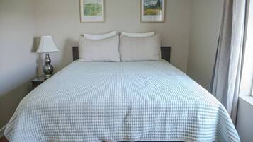 A standard hotel room with a bed, a nightstand with a lamp, and two framed pictures on the wall.
