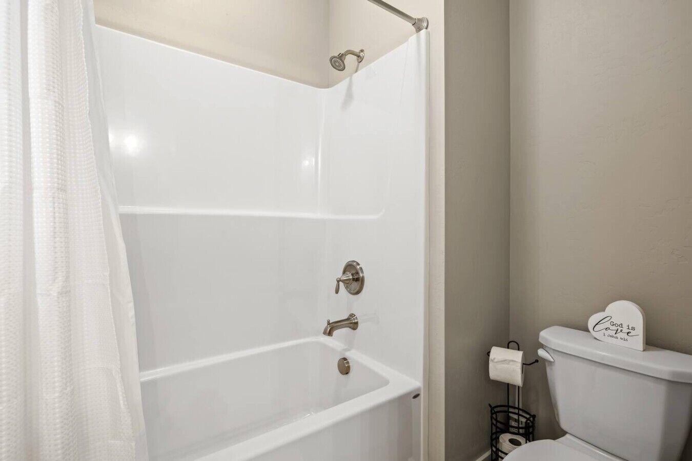 Une salle de bain avec une baignoire blanche, des toilettes et un rideau de douche.