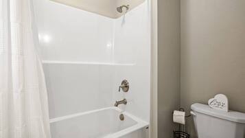 Une salle de bain avec une baignoire blanche, des toilettes et un rideau de douche.
