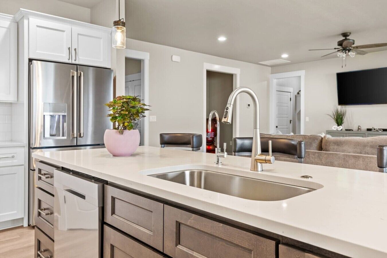 A modern kitchen with a stainless steel refrigerator, a sink, and a potted plant.