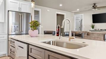 A modern kitchen with a stainless steel refrigerator, a sink, and a potted plant.