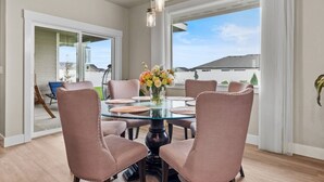 A dining area with a glass table, six chairs, and a vase of flowers. - Spacious 3BR Home + Office | Work & Relax (Boardman)