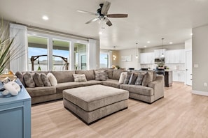 A spacious living room with a sectional sofa, a ceiling fan, and a view to the outside.