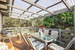 Eine Terrass mit Tisch und Stühlen, umgeben von einem Holzzaun und Glasscheiben.