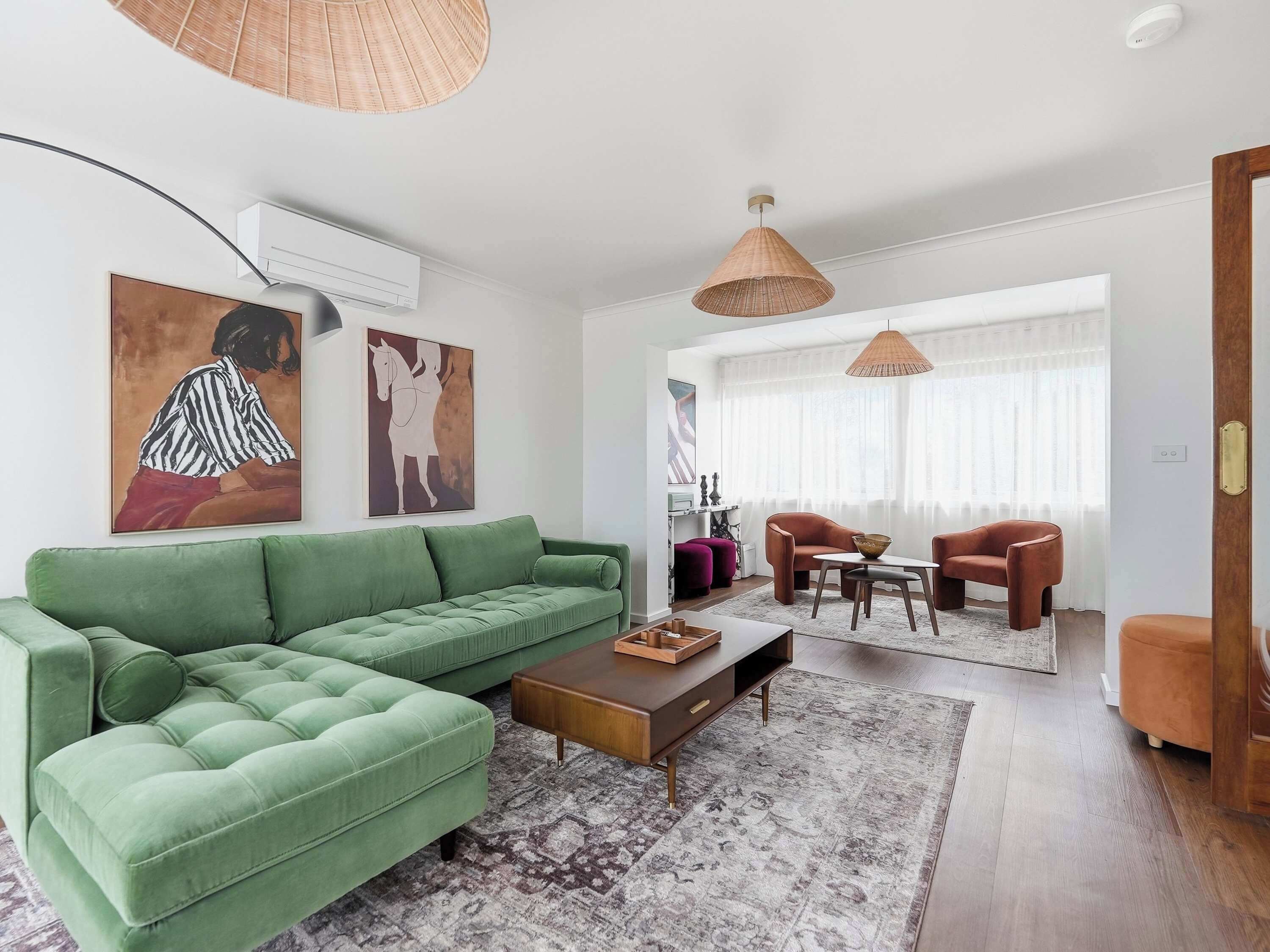 Un salon moderne avec un canapé vert, une table basse en bois et un coin repas comprenant deux chaises.